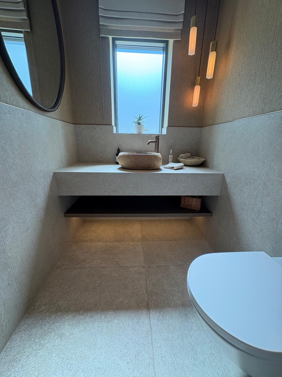 Freestanding bath against a book-matched marble feature wall with skylight