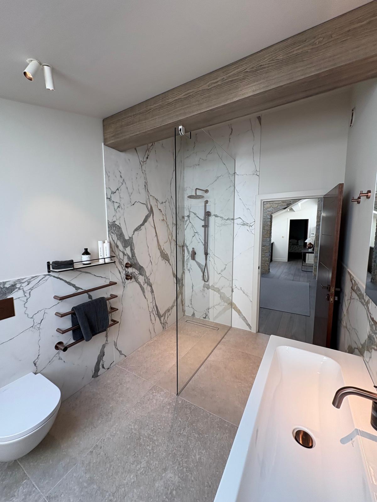 Walk-in shower in book-matched white and grey marble with brass fittings