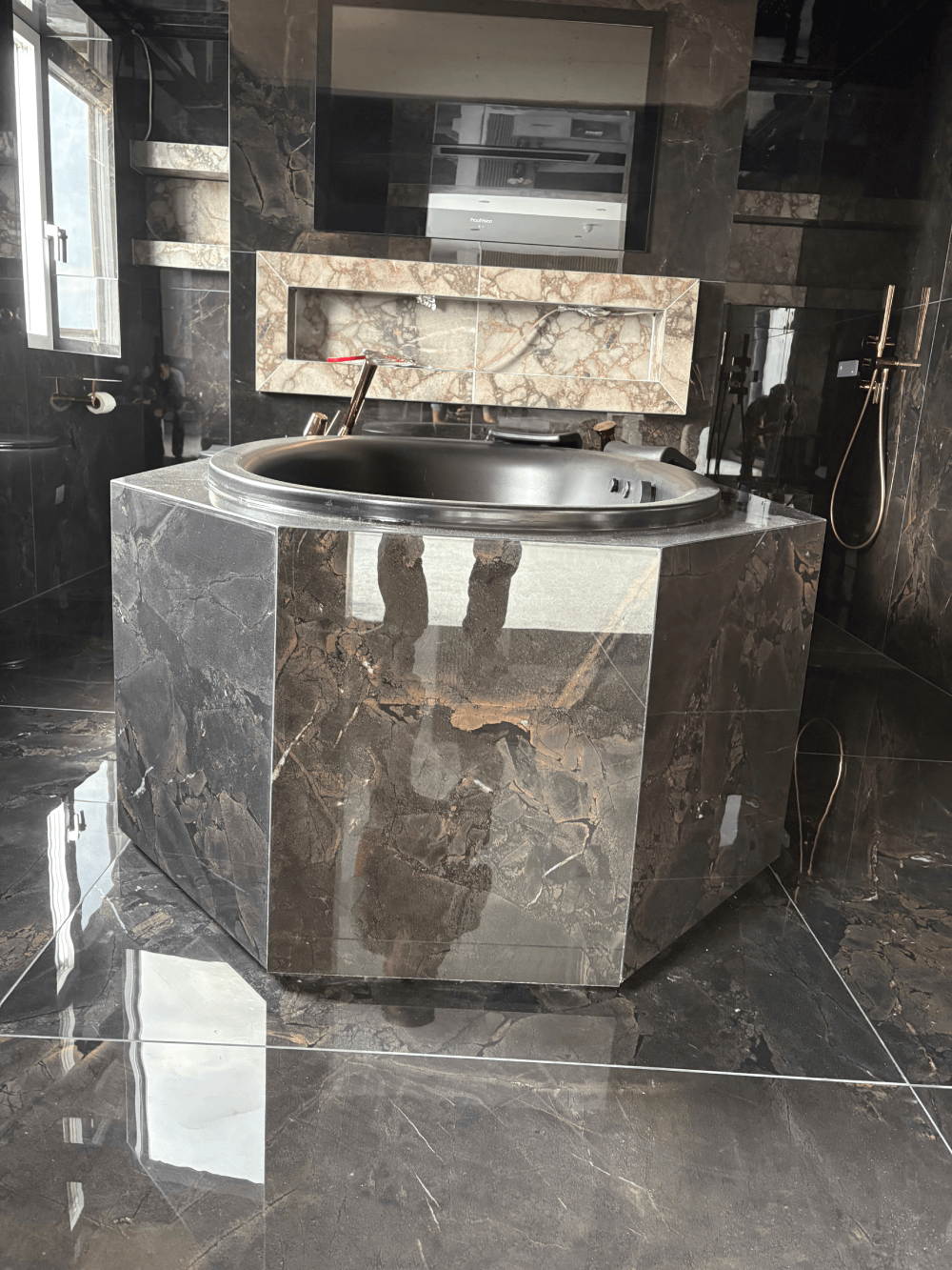 Stone-clad bath surround with inset mirror and stone feature panel