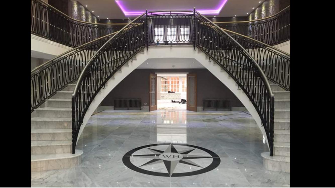 Grand entrance hall with twin curved marble staircases and inlaid marble floor medallion